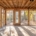 Sunroom interior under construction with wooden beams, large glass windows allowing natural light, and a spacious layout for indoor-outdoor living.